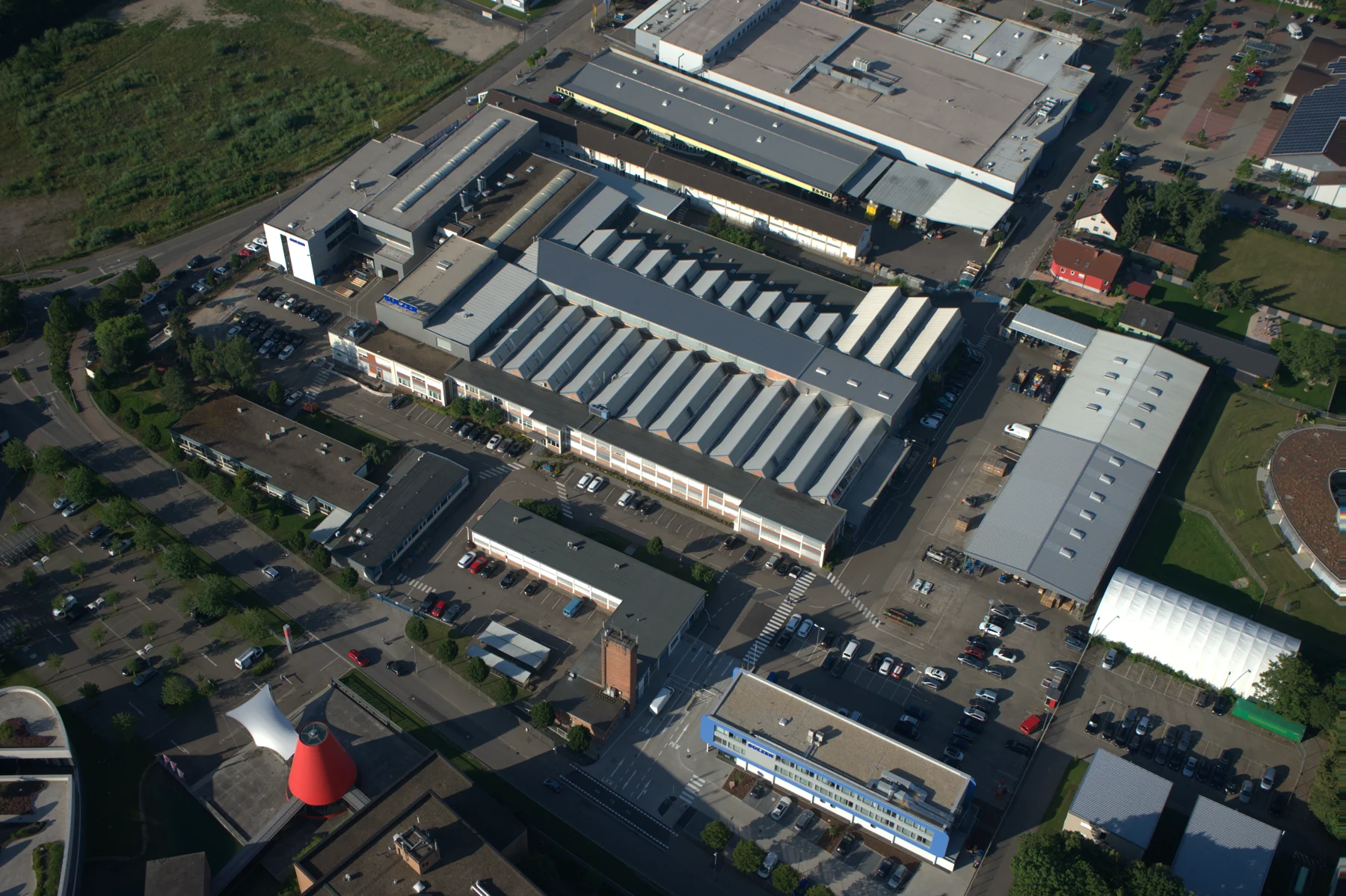 Schrägluftaufnahme des Sulzer-Firmengeländes in Bruchsal mit Produktionshallen, Verwaltungsgebäude und Zufahrten